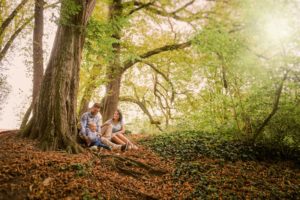 Familyfotos im Kastaniengarten in Roggenburg mit einer schöne Lichtstimmung. Die Familie sitzt an einem Baum, der an einem Hang steht