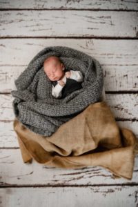 Babyfoto im Studio auf Holzboden in weisslackiert mit grauer Decke und Kartoffelsack