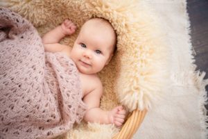 Baby lacht in die Kamera auf Schafsfell mit rosa Decke - Fotograf Ulm, Neu-Ulm, Illertissen, Memmingen, Krumbach, Senden, Günzburg, Weißenhorn