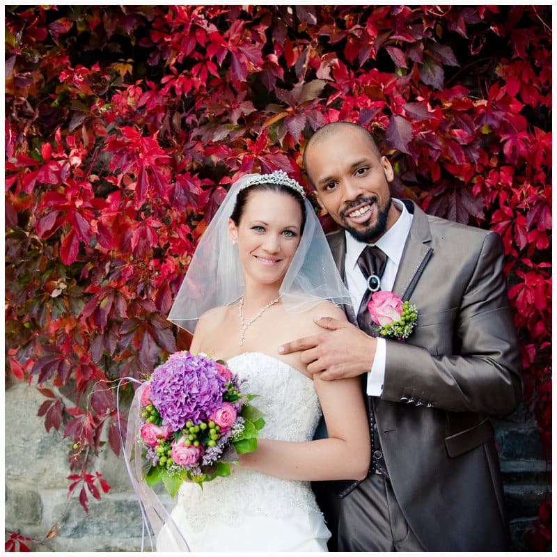 Brautpaar vor roten Blumen