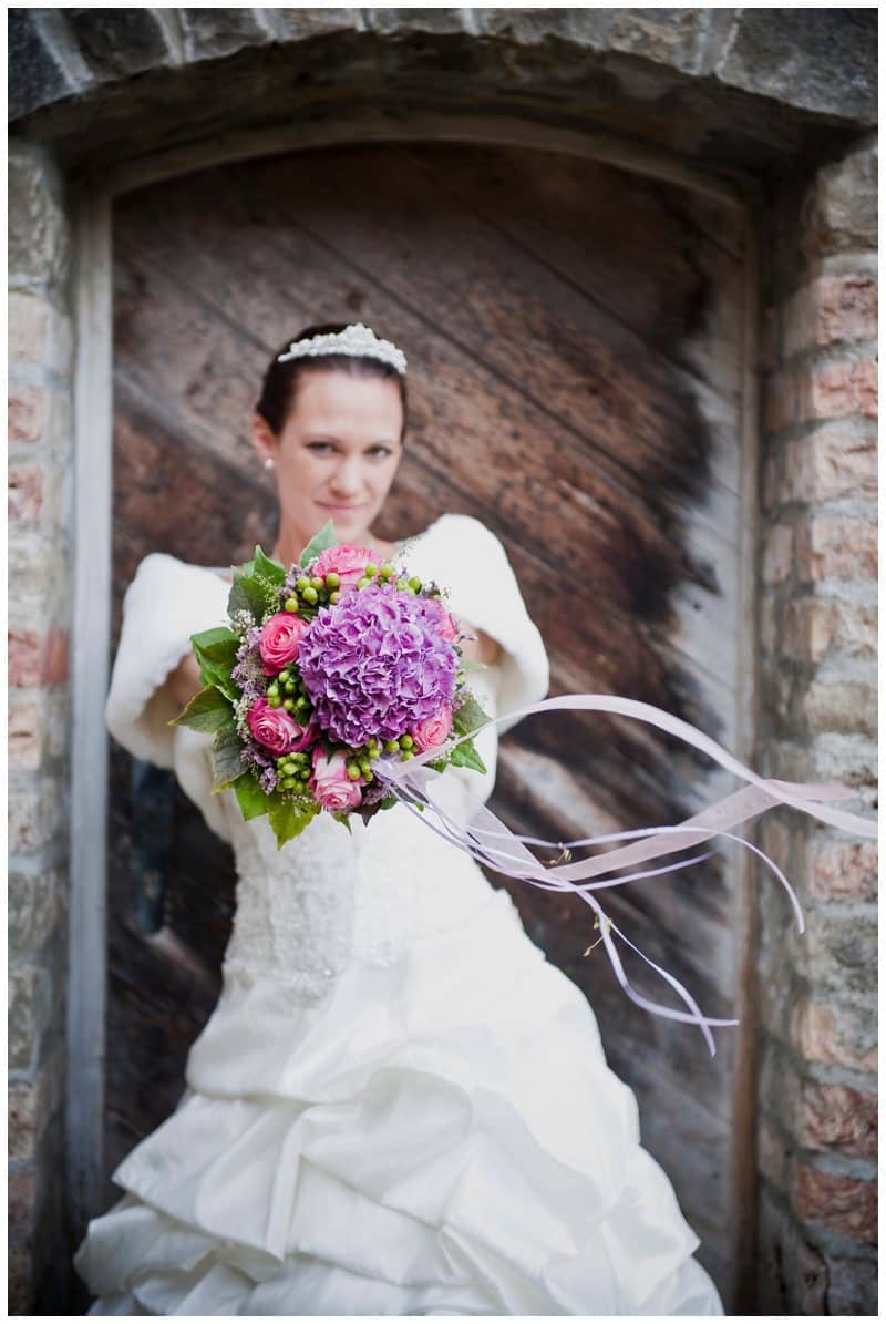 Braut zielt mit Strauß auf Fotograf