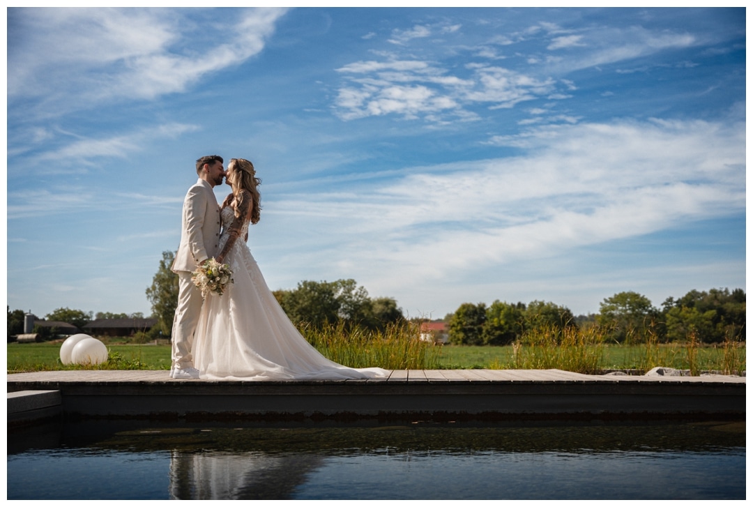 Weitwinkelfoto Braut steht auf dem Steg mit blauem Himmel und Wolken