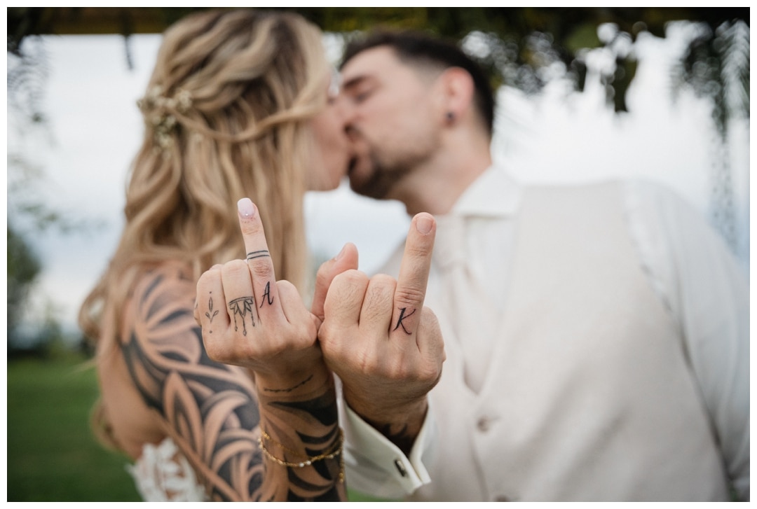 Tattoos auf einer Hochzeit stechen. Das Brautpaar zeigt die frisch gestochenen Tattoos in die Kamera