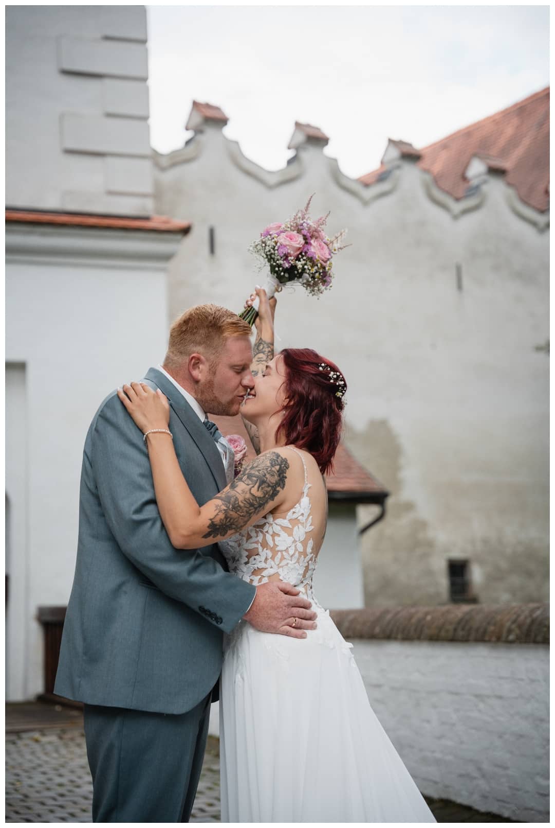 Das Brautpaar küsst sich auf der Zugbrücke beim Ein weitwinkelfoto Schloss Neuburg an der Kammel