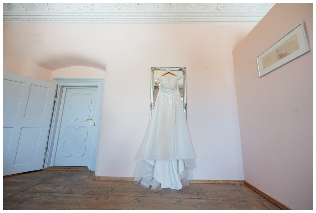 Brautkleid hängt an einem Wandspiegel im Schloss Neuburg